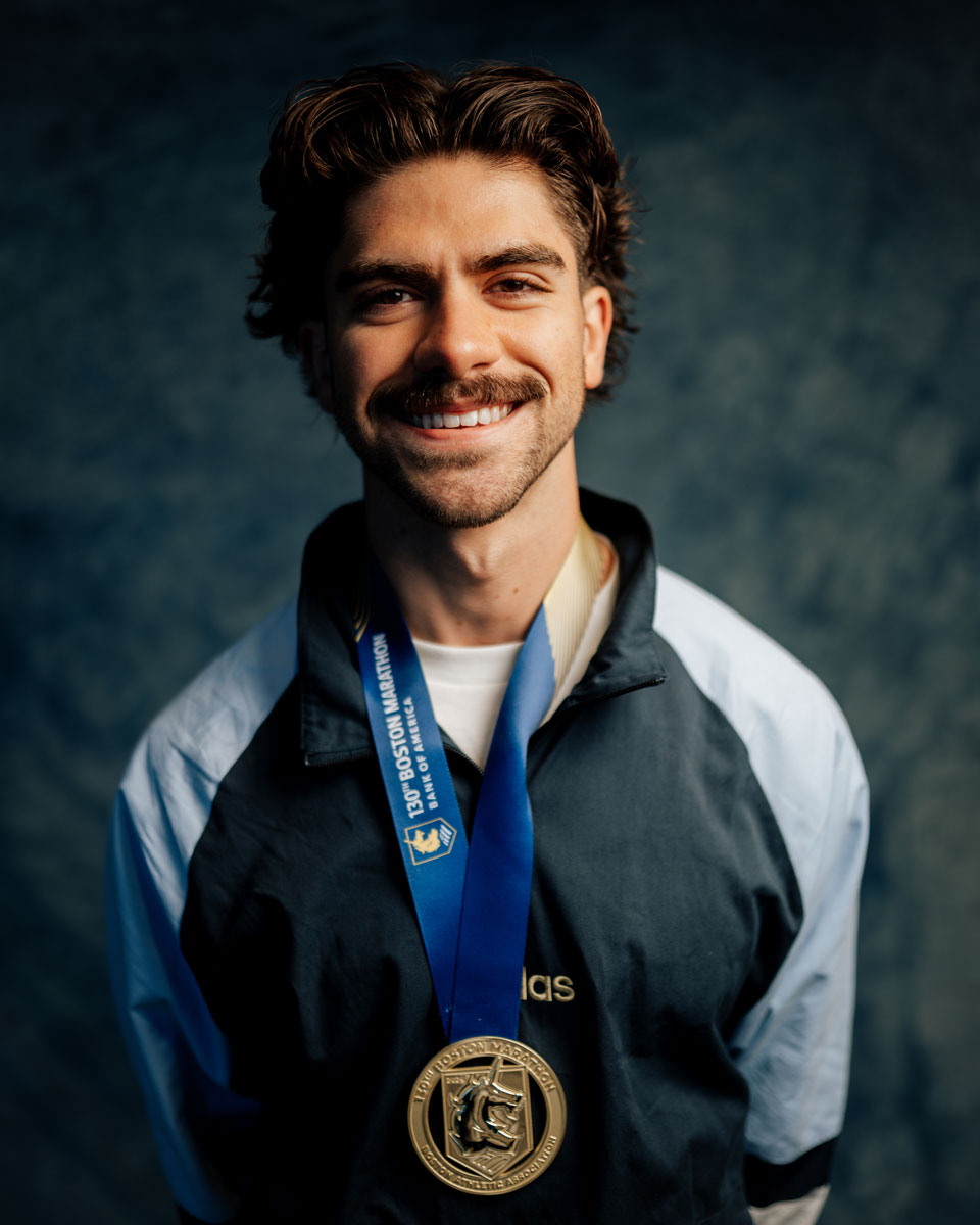 The coach is smiling while wearing the medal.